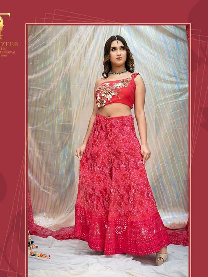 Visit us for the latest festive outfits, like this vibrant red sharara set with a one-shoulder embroidered blouse.