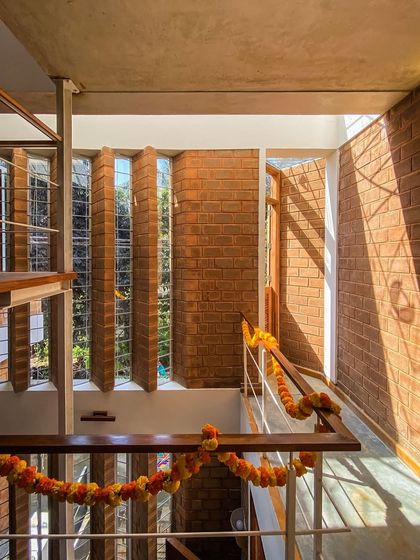 Sunlight streams through the pivoted windows of the Divyadarshan home, illuminating the exposed brick walls and staircase. This demonstrates our core principle of using natural light to animate a space.