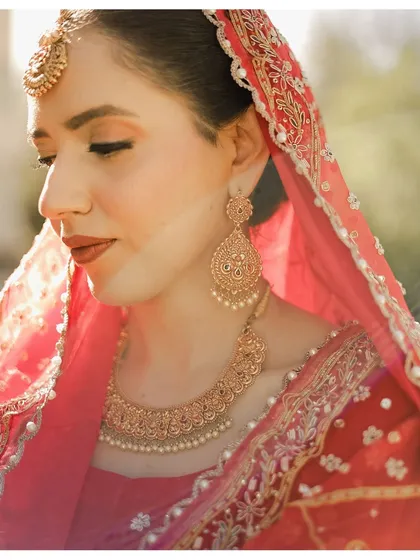 A close-up portrait of the bride Ganeemat, focusing on her flawless makeup and traditional jewelry. The soft, natural light gives her a radiant glow on her wedding day.