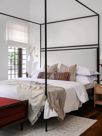 I believe a master bedroom should be a sanctuary. Here, I designed a custom four-poster bed to create a sense of retreat, layering soft textiles and warm wood tones. The arched doorway offers a glimpse into the bespoke walk-in closet, showing how I integrate practical needs into a serene design.