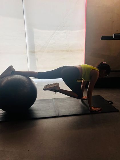 Here, I'm performing a knee tuck on the stability ball. This dynamic movement is a powerful core exercise that targets the lower abdominals as you draw your knees in towards your chest.