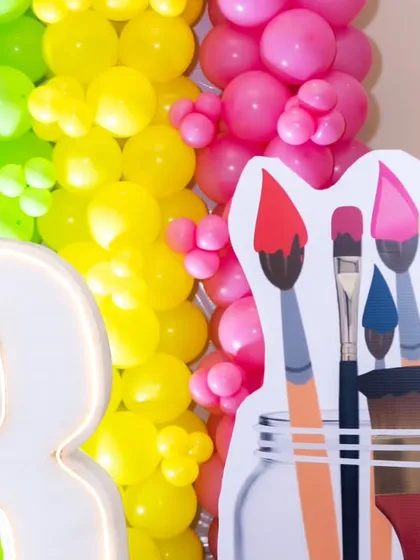 A close-up of the Art and Paint party decor, highlighting the custom paintbrush cut-outs and the bright, multi-colored balloon wall.