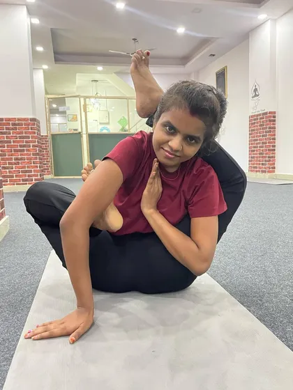 A student holds an impressive and complex leg-behind-the-head pose, showcasing extreme flexibility and dedication.