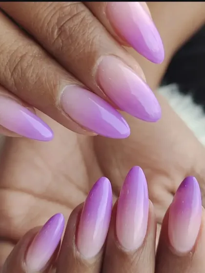 We create seamless color blends with our ombre nail services. This set shows a beautiful fade from a natural base to a vibrant lilac on long, almond-shaped extensions.
