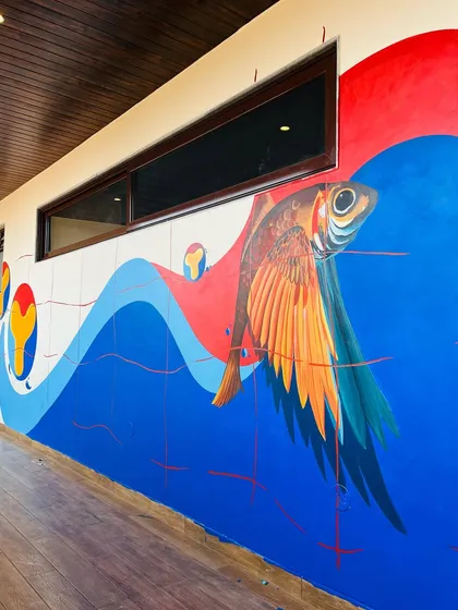 A surrealist mural featuring a flying fish soaring over waves of blue and red. This piece, titled 'Padayon', which means to move on, was created to bring a sense of wonder and imagination to a commercial space.
