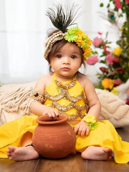 Another beautiful portrait of our little Radha, ready to steal hearts with her matki. The details in her costume and the floral background are perfect for the occasion.