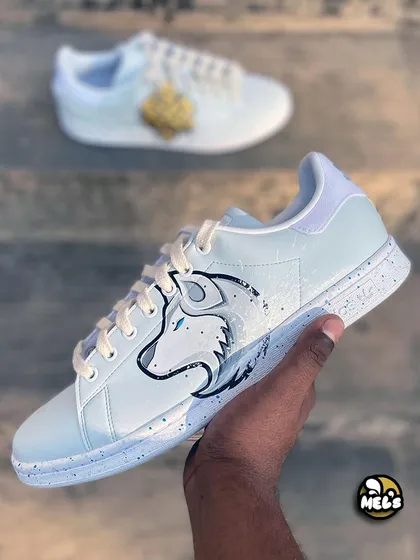 A hand-held shot of the white wolf custom sneaker, with the Karma shoe blurred in the background.