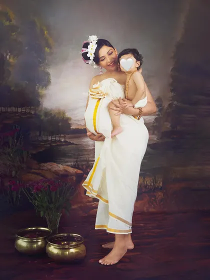 A beautiful moment between a mother and her first child as they await the new baby. Dressed in a traditional Kasavu saree, she holds her son close, creating a portrait full of love and heritage.