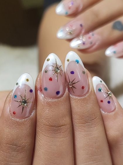 Another fun and festive design for Navratri. These almond nails feature a modern French tip, a sheer base with colorful polka dots, and sparkling starburst charms for a playful yet glamorous look.