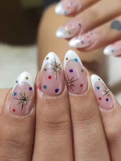 Another fun and festive design for Navratri. These almond nails feature a modern French tip, a sheer base with colorful polka dots, and sparkling starburst charms for a playful yet glamorous look.