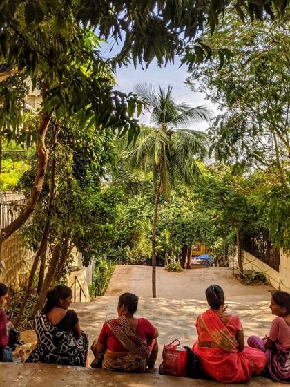 A group of women enjoying a peaceful moment, seated on the steps and framed by lush greenery. This image captures the essence of what we strive for: creating tranquil, green pockets within the bustling city.
