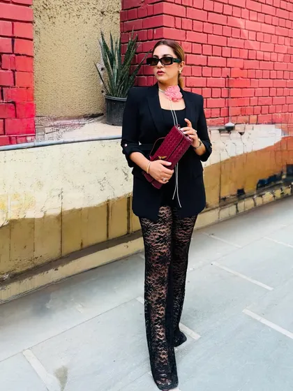 It's not over until I win. This look is all about power and confidence, featuring a black blazer over lace pants, cinched with a belt. The pop of color from the wine bag and flower choker adds a unique touch.