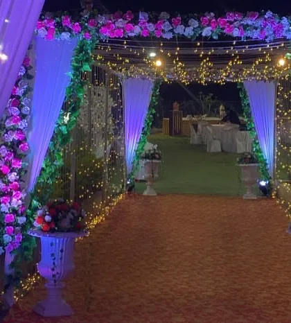 A beautiful floral entrance arch for an evening reception. The combination of pink and white flowers, greenery, and soft lighting creates a romantic and welcoming pathway for guests.