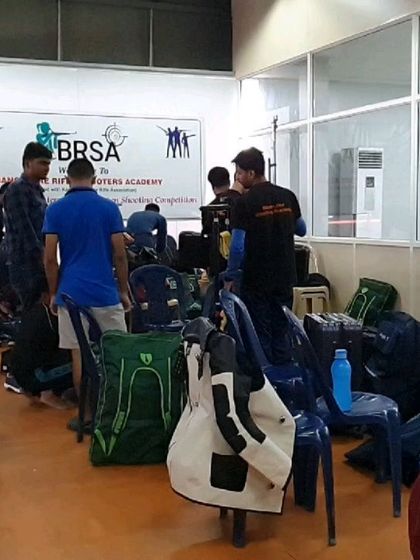 The prep area during a competition, filled with shooters' kits and equipment. It shows the serious and bustling atmosphere of a tournament day.