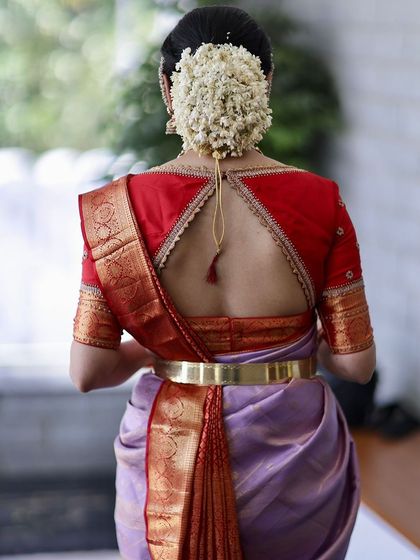 A stunning back view of a bride in a lavender saree with a red blouse featuring a statement cut-out design.