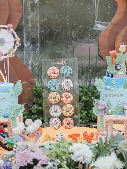 The dessert table was a wild adventure in itself, with two stunning cakes and an array of animal-themed treats set against a custom backdrop, complete with a miniature train track.
