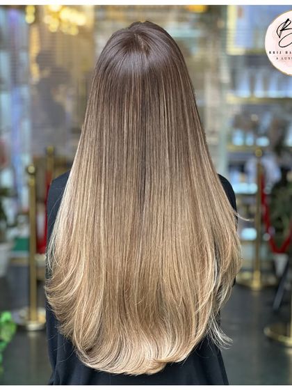 The back view showcases the stunning gradient and sleek finish of this ash blonde look.