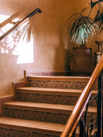 A single, well-chosen plant can transform an indoor corner. Here, a large terracotta pot with a palm plant adds a touch of rustic elegance and natural beauty to a staircase landing.