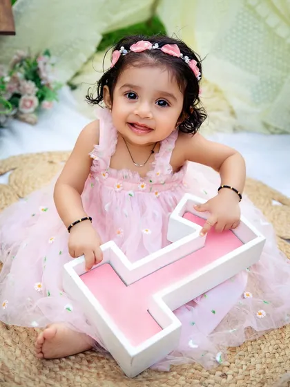 Holding her number one. This is a classic and adorable pose for a first birthday, celebrating this huge milestone in a sweet and simple way.