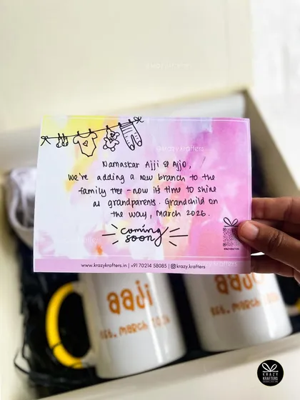 The personalized note is the heart of the hamper. This one, announcing a new grandchild to 'Aaji & Aajo', is paired with custom mugs to create a deeply emotional reveal.