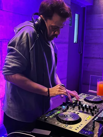 A candid shot of me mixing during a rooftop party. Even in a more relaxed setting, my focus is on creating a seamless musical journey.