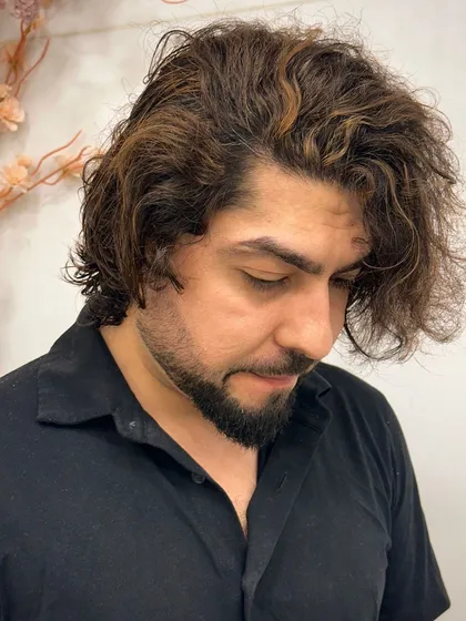 An example of our men's coloring services. This client has added light brown highlights to his long, wavy hair for a stylish, sun-kissed look.