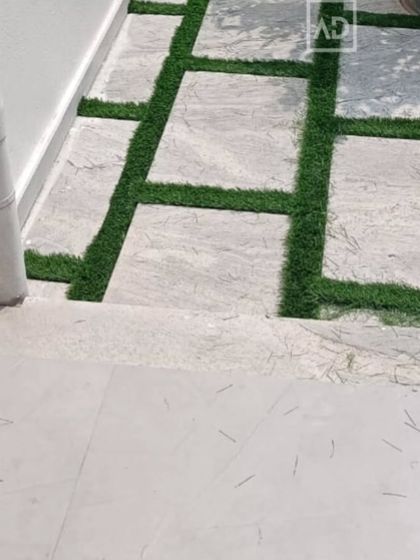A close-up of the artificial grass laid between pavers, showing the clean lines and professional finish of the installation.