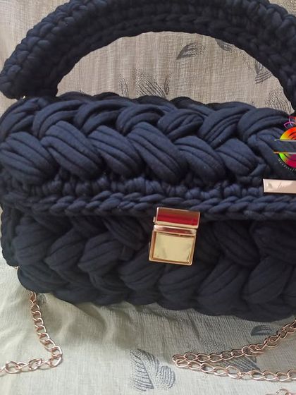 The black t-shirt yarn handbag, a timeless and elegant accessory. The deep black color makes the gold hardware pop, creating a sophisticated look for any occasion.