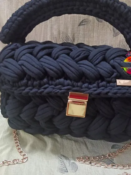 The black t-shirt yarn handbag, a timeless and elegant accessory. The deep black color makes the gold hardware pop, creating a sophisticated look for any occasion.