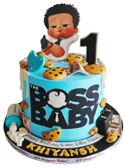 A fun and playful Boss Baby cake design. This whipped cream cake is covered in edible cookies and money, with the Boss Baby character ready to take charge of his first birthday party.