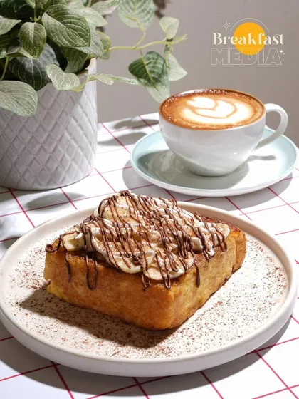A perfect pairing of coffee and dessert. This shot uses soft, natural light to highlight the texture of the French toast and the latte art, making it an ideal image for a cafe's social media or menu.