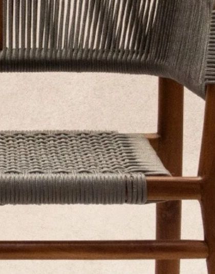 A close-up detail of the 'Tali' chair. The grey rope is expertly woven and wrapped around the solid teak frame, creating a piece that is comfortable, chic, and light.