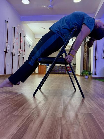 Extending fully in a chair-supported pose, lengthening the entire front side of the body.