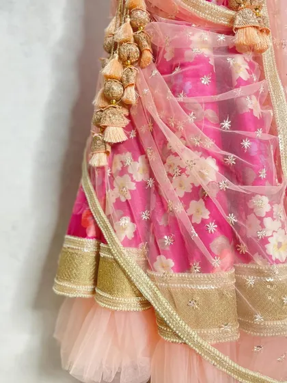 A close-up shot showcasing the layers of the floral lehenga, with a tulle ruffle peeking out from under the hem and the intricate dangling tassels.