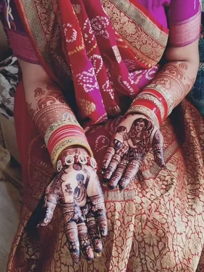 The beautiful, rich stain of a bridal mehendi featuring custom portraits, seen here with the bride's traditional attire.