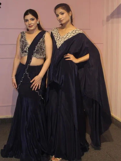 Two stunning navy blue outfits from our 'DESIRE' collection. On the left, a draped sharara with an embroidered blouse, and on the right, a kaftan with an embellished neckline.