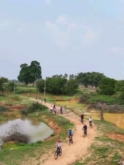 An aerial view of a group crossing a causeway between two ponds. Our Nandi Countryside ride is full of these interesting and scenic sections.