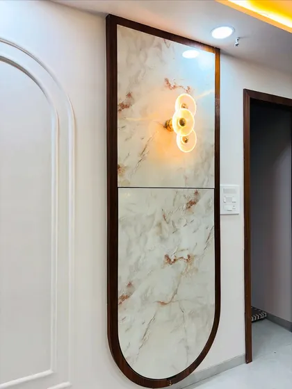The folding table in its closed position. It becomes a decorative wall panel with an elegant marble finish and a stylish light fixture, proving that functional furniture can also be beautiful.