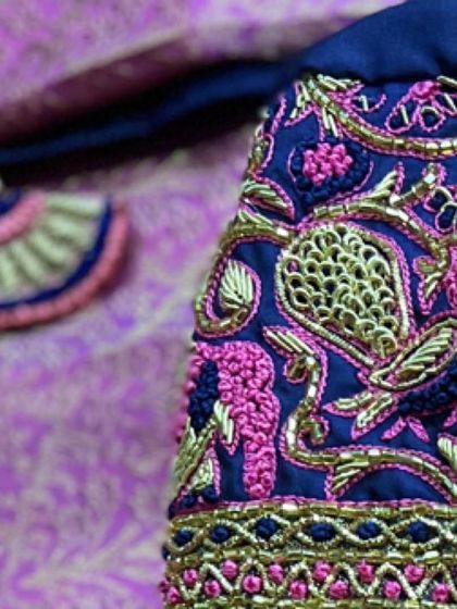 A detailed shot of the intricate peacock and elephant motifs on this navy blue and pink blouse. The fine knot work and zardozi create a beautiful texture.