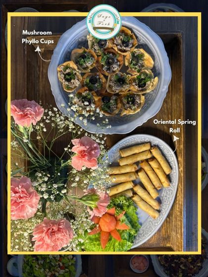 A beautiful platter featuring our Mushroom Phyllo Cups and Oriental Spring Rolls, adorned with fresh flowers. A perfect appetizer combination.