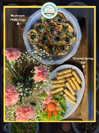 A beautiful gifting platter featuring my Mushroom Phyllo Cups and Oriental Spring Rolls, garnished with fresh flowers. It's a gift that is sure to impress.