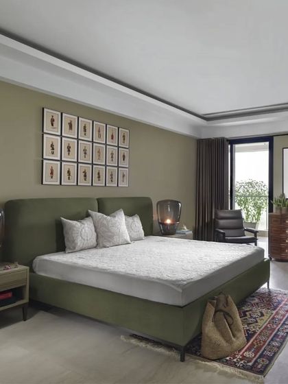 The master bedroom in the Caitriona apartment is a spacious retreat with serene views of the golf course. The colour palette is calm and earthy, with an olive green upholstered bed and a collection of Kalighat paintings creating a restful and sophisticated atmosphere.