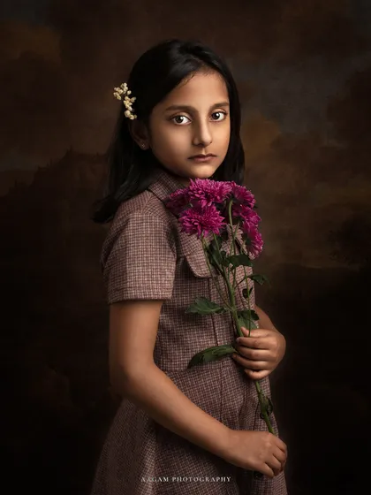 A timeless expression. This young girl, holding a bouquet of flowers, looks like a character from a historical novel. The lighting and mood are purely classical.