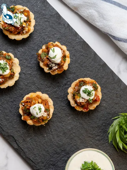 These Mexican Tarts are a fiesta in a bite. The crispy tart shells are filled with a zesty mix of beans, corn, and spices, then topped with a dollop of sour cream, offering a burst of flavor perfect for any celebration.