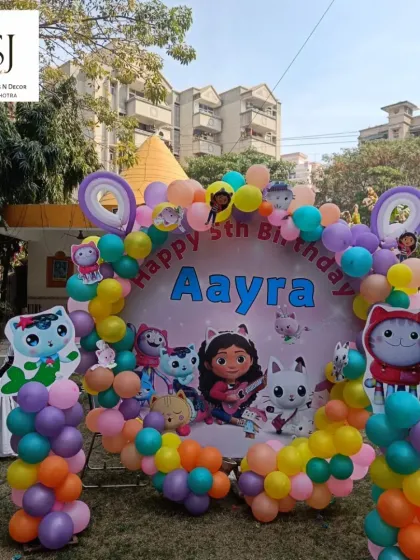A whimsical Gabby's Dollhouse 5th birthday party for Aayra, featuring a colourful backdrop with all the characters from the show.