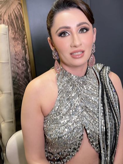 A glamorous look in a stunning silver and black saree. The makeup is drenched in shimmer with a soft glow, creating a breathtakingly angelic appearance.