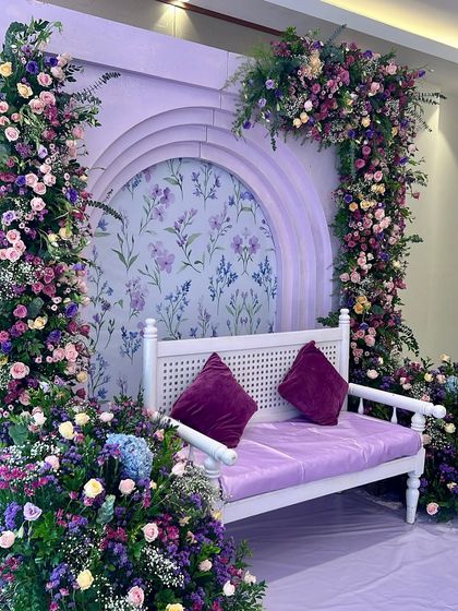 An Aqeeqah decor setup in a stunning lavender and purple color palette. We framed a floral-patterned backdrop with lush arches of fresh flowers for a truly luxurious feel.