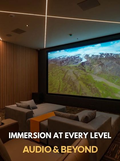 A look inside one of our showroom's demonstration theaters. This space combines modern aesthetics with high-performance technology, featuring wood-paneled acoustic walls, recessed ceiling speakers for Dolby Atmos, and a mix of sofa and recliner seating.