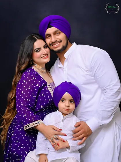 A classic family portrait that radiates warmth and togetherness. With coordinated outfits against a simple, dark backdrop, the focus remains entirely on the family's bright smiles and loving bond.