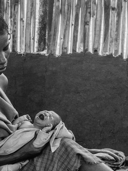 A mother holds her crying newborn, a poignant image used to announce the "Endangered Species" exhibition. The photo encapsulates the anxieties and hopes of families facing malnutrition.